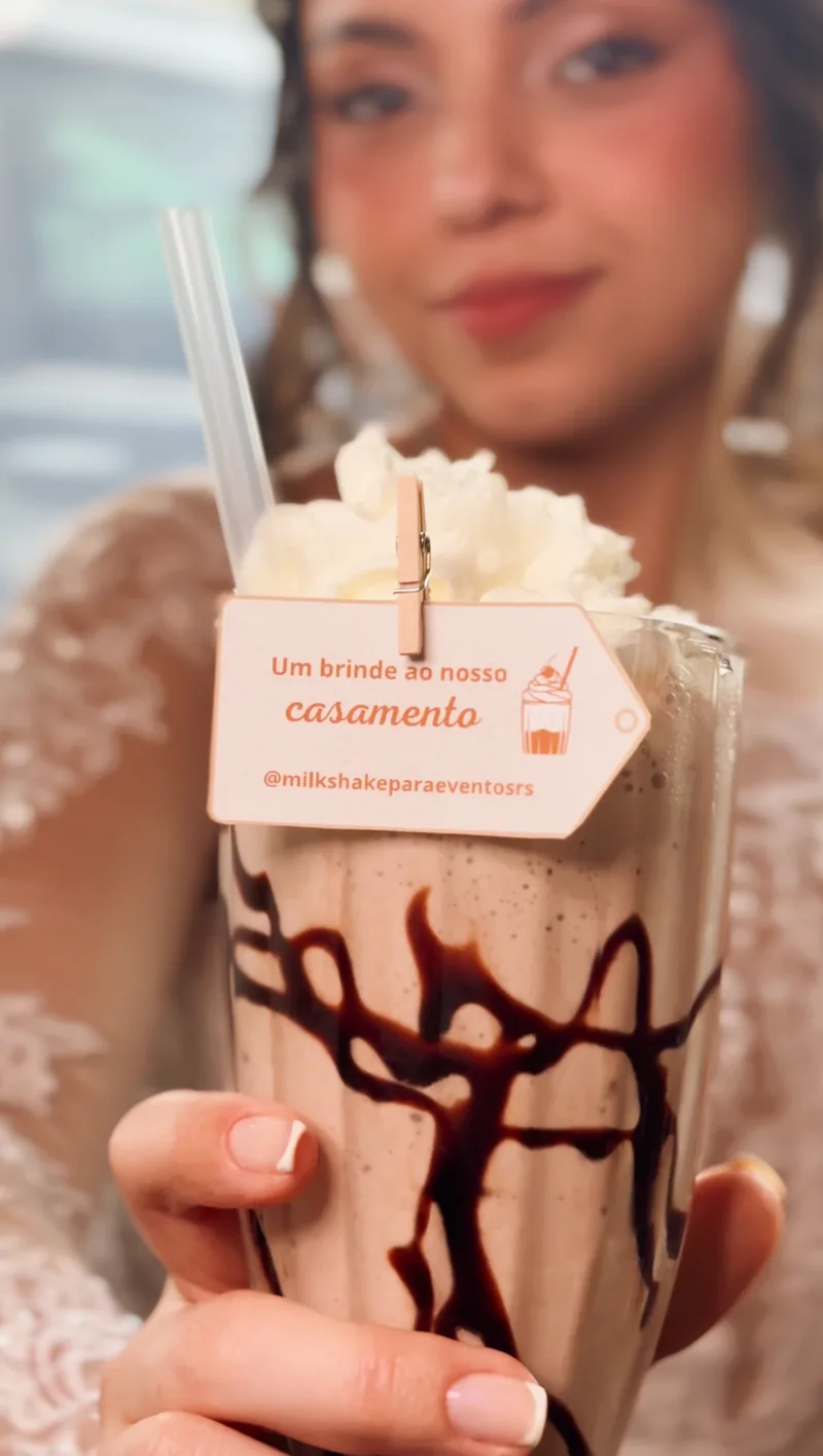 Milkshake da Celebre com chantilly e tag de casamento, segurado por uma convidada